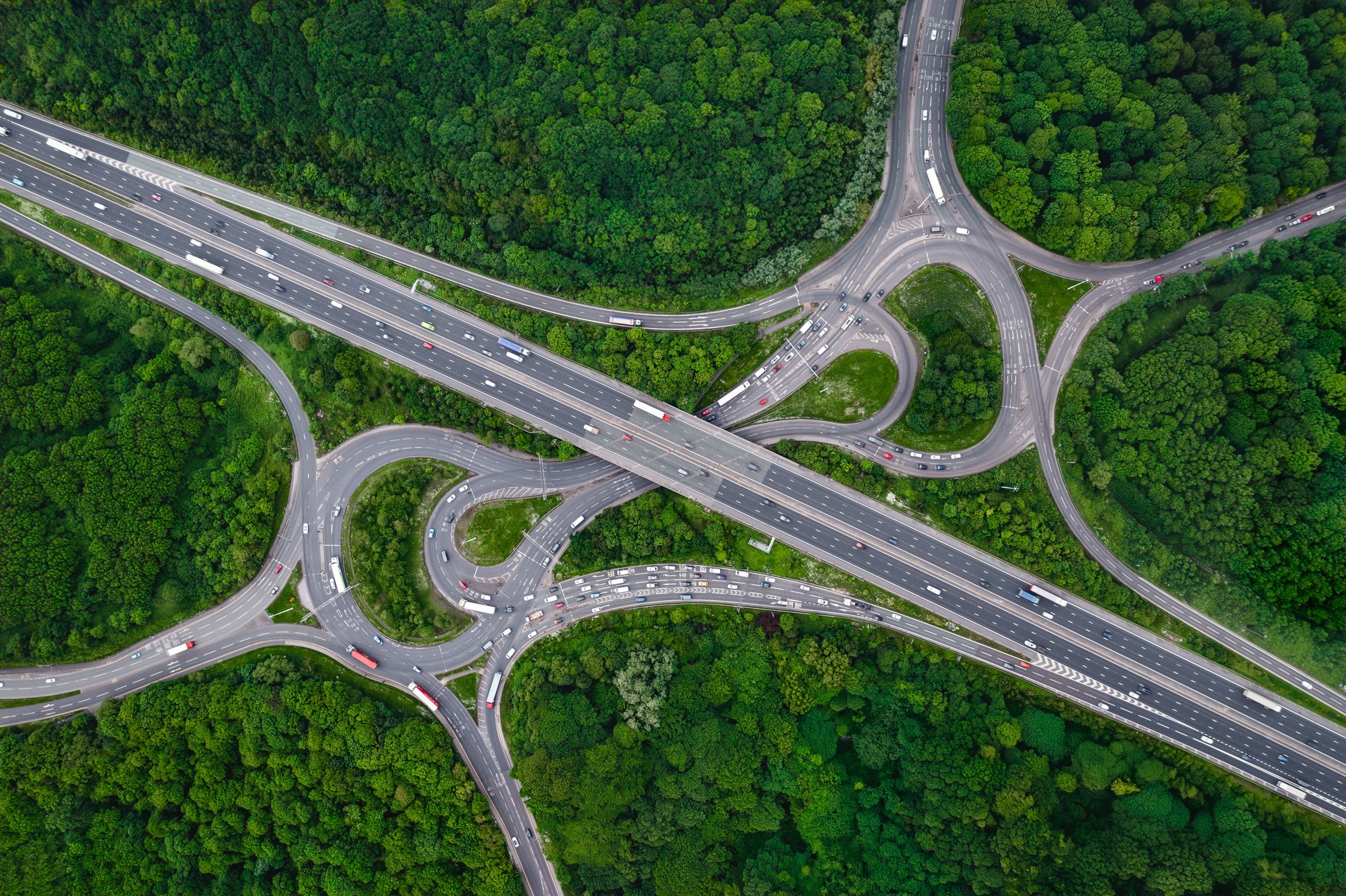 Aerial view above a complex motorway junction cutting through green forest